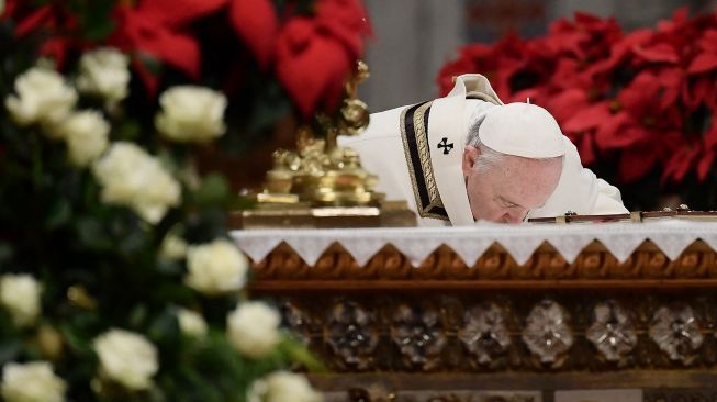 
Paus Fransiskus mencium Altar selama misa Malam Natal di Basilika Santo Petrus di Vatikan, pada 24 Desember 2021.Filippo MONTEFORTE / AFP