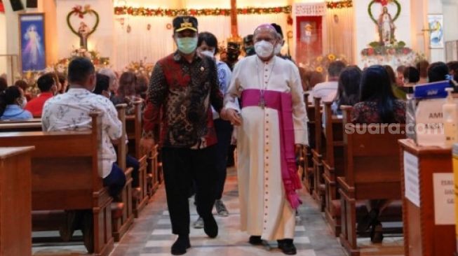 Andi Sudirman berjalan sambil memegang tangan seorang pendeta saat misa malam Natal di Kota Makassar, Jumat 24 Desember 2021 [SuaraSulsel.id/Istimewa]