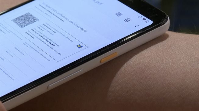Direktur DSruptive Subdermals, Hannes Sjoblad memindai implan di lengan bawahnya dengan smartphone untuk mengungkapkan kartu kesehatannya di Stockholm, Swedia, pada (20/12/2021). [VIKEN KANTARCI / AFP]