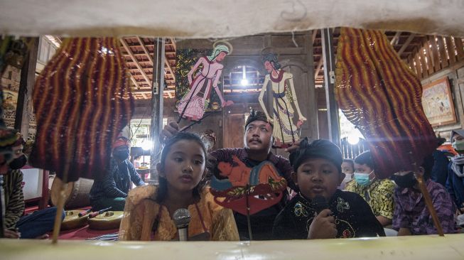 Dalang Indra Suroinggeno (tengah) memainkan wayang kulit bertema Natal di Bantul, Yogyakarta, pada (24/12/2021). [AGUNG SUPRIYANTO / AFP]