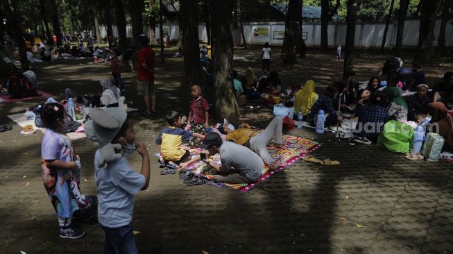 Pengunjung beristirahat di Taman Margasatwa Ragunan, Jakarta, Minggu (26/12/2021). [Suara.com/Angga Budhiyanto]