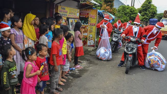 Warga berpakaian "Santa Claus" membagikan bingkisan Natal di Lingkungan Jadimulya, Kota Banjar, Jawa Barat, Sabtu (25/12/2021). [ANTARA FOTO/Adeng Bustomi]