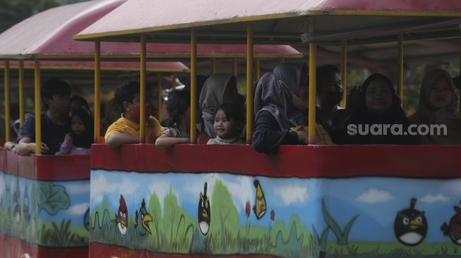 Pengunjung menaiki mobil wisata di Taman Margasatwa Ragunan, Jakarta, Minggu (26/12/2021). [Suara.com/Angga Budhiyanto]