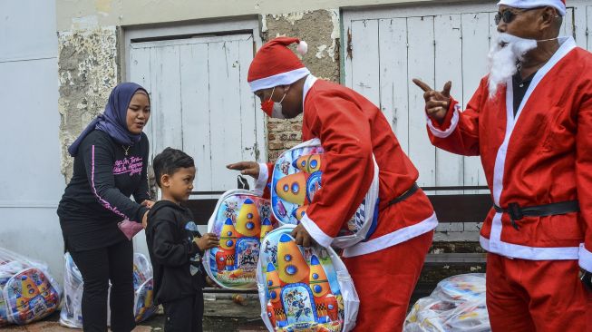 Warga berpakaian "Santa Claus" membagikan bingkisan Natal di Halaman Gereja Katolik Santo Filipus, Lingkungan Jadimulya, Kota Banjar, Jawa Barat, Sabtu (25/12/2021). [ANTARA FOTO/Adeng Bustomi]