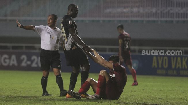 Penyerang Martapura Dewa United Herman Dzumafo (kedua kiri) membantu pemain belakang Persis Solo Fabiano Rosa Beltrame (kedua kanan) untuk berdiri dalam pertandingan semifinal Liga 2 antara Martapura Dewa United melawan Persis Solo di Stadion Pakansari, Bogor, Jawa Barat, Senin (27/12/2021). [Suara.com/Angga Budhiyanto]