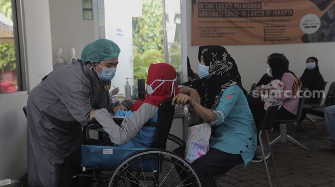 Petugas kesehatan memeriksa kesehatan warga yang akan melakukan tes usap (swab test) antigen di Puskesmas Kecamatan Mampang Prapatan, Jakarta Selatan, Senin (27/12/2021). [Suara.com/Angga Budhiyanto]