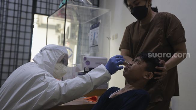 Petugas kesehatan melakukan tes usap (swab test) PCR kepada warga di Puskesmas Kecamatan Mampang Prapatan, Jakarta Selatan, Senin (27/12/2021). [Suara.com/Angga Budhiyanto]