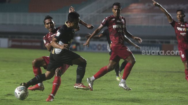 Pemain belakang Persis Solo Abduh Lestaluhu (kiri) menghadang gelandang Martapura Dewa United Gufroni Al Maruf (kedua kiri) dalam pertandingan semifinal Liga 2 antara Martapura Dewa United melawan Persis Solo di Stadion Pakansari, Bogor, Jawa Barat, Senin (27/12/2021). [Suara.com/Angga Budhiyanto]