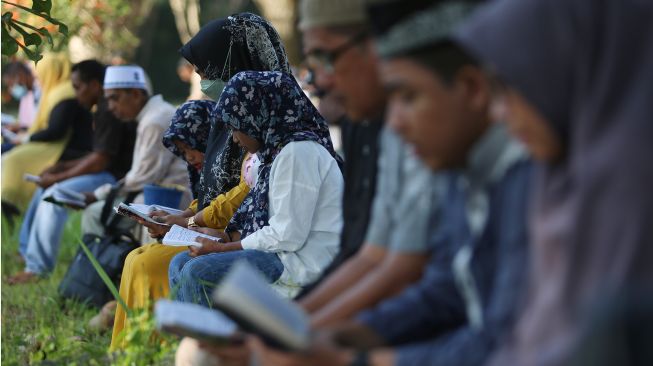 Sejumlah warga membaca surat yasin dan berdoa untuk keluarganya yang meninggal akibat bencana gempa dan tsunami di kuburan massal korban tsunami Aceh Besar, Aceh, Minggu (26/12/2021). ANTARA FOTO/Syifa Yulinnas