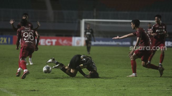 Gelandang Martapura Dewa United Rangga Muslim (tengah) terjatuh selama pertandingan semifinal Liga 2 antara Martapura Dewa United melawan Persis Solo di Stadion Pakansari, Bogor, Jawa Barat, Senin (27/12/2021). [Suara.com/Angga Budhiyanto]