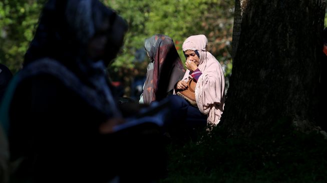 Sejumlah warga membaca surat yasin dan berdoa untuk keluarganya yang meninggal akibat bencana gempa dan tsunami di kuburan massal korban tsunami Aceh Besar, Aceh, Minggu (26/12/2021). ANTARA FOTO/Syifa Yulinnas