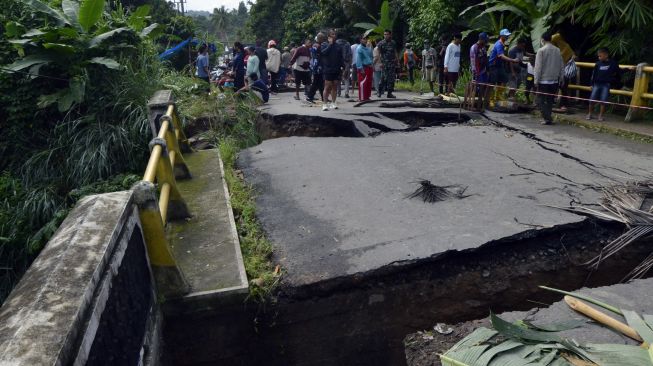 Warga melihat kondisi jembatan Way Gebang yang putus di Desa Gebang, Teluk Pandan, Pesawaran, Lampung, Senin, (27/12/2021).  ANTARA FOTO/Ardiansyah