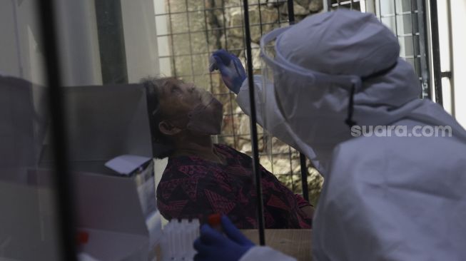 Petugas kesehatan melakukan tes usap (swab test) antigen kepada warga di Puskesmas Kecamatan Mampang Prapatan, Jakarta Selatan, Senin (27/12/2021). [Suara.com/Angga Budhiyanto]