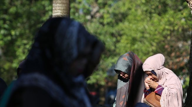 Sejumlah warga membaca surat yasin dan berdoa untuk keluarganya yang meninggal akibat bencana gempa dan tsunami di kuburan massal korban tsunami Aceh Besar, Aceh, Minggu (26/12/2021). ANTARA FOTO/Syifa Yulinnas