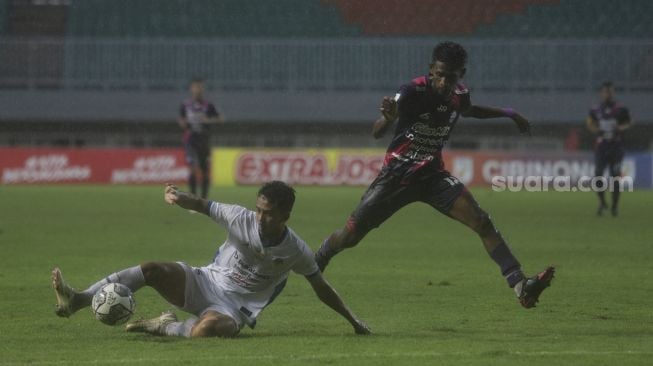 Pemain belakang PSIM Yogyakarta Taufik Hidayat (kiri) merebut bola dari penyerang RANS Cilegon FC Jujun Junaedi dalam pertandingan semifinal Liga 2 antara RANS Cilegon FC melawan PSIM Yogyakarta di Stadion Pakansari, Bogor, Jawa Barat, Senin (27/12/2021). [Suara.com/Angga Budhiyanto]