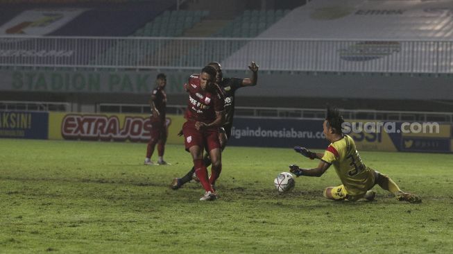 Penjaga gawang Martapura Dewa United Rivky Mokodompit (kanan) menepis tendangan dari penyerang Persis Solo Alberto Goncalves dalam pertandingan semifinal Liga 2 antara Martapura Dewa United melawan Persis Solo di Stadion Pakansari, Bogor, Jawa Barat, Senin (27/12/2021). [Suara.com/Angga Budhiyanto]