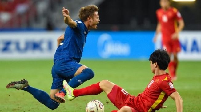 Pemain Thailand Theerathon Bunmathan (kiri) ditekel pemain Vietnam di leg pertama semifinal Piala AFF 2020 di Stadion Nasional, Singapura, Kamis (23/12/2021). [AFP]