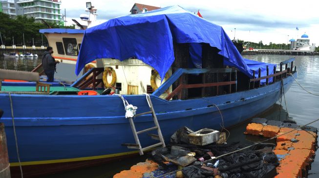 Seorang wartawan berada di atas kapal wisata KM Banawa 28 usai terbakar di anjungan Pantai Losari, Makassar, Sulawesi Selatan, Senin (27/12/2021). ANTARA FOTO/Abriawan Abhe