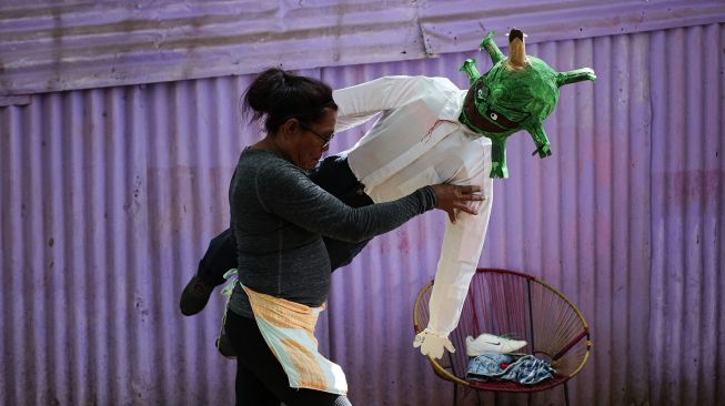 Seorang perempuan memegang boneka buatan tangan yang menggambarkan COVID-19 varian Omicron di Managua, Nikaragua, pada (27/12/2021). [OSWALDO RIVAS / AFP]