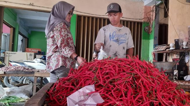 Salah satu pedagang bumbu dapur di Pasar Kranggot, Cilegon melayani pembeli, Kamis (30/12/2021). [Suara.com/Firasat Nikmatullah]