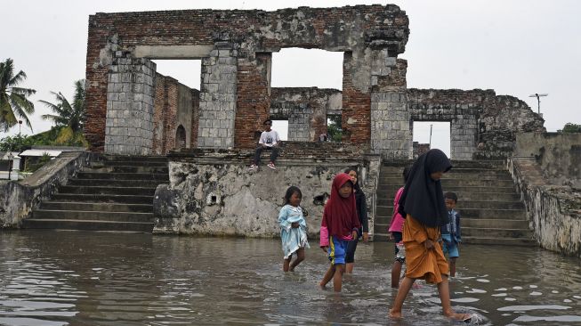 Sejumlah anak bermain di area cagar budaya Keraton Kaibon yang terendam banjir di Kasemen, Serang, Banten, Kamis (30/12/2021). [ANTARA FOTO/Asep Fathulrahman]