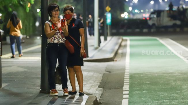 Warga berswafoto saat pemberlakuan Crowd Free Night di Kawasan Bundaran HI, Jakarta Pusat, Jumat (31/12/2021). [Suara.com/Alfian Winanto]