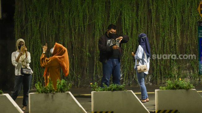 Warga berswafoto saat pemberlakuan Crowd Free Night di Kawasan Bundaran HI, Jakarta Pusat, Jumat (31/12/2021). [Suara.com/Alfian Winanto]