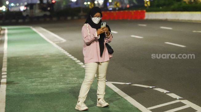 Warga berswafoto saat pemberlakuan Crowd Free Night di Kawasan Bundaran HI, Jakarta Pusat, Jumat (31/12/2021). [Suara.com/Alfian Winanto]