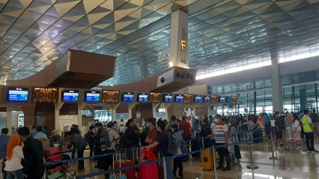 Pengguna jasa penerbangan mengantre di Bandara Soekarno-Hatta atau Bandara Soetta, Jumat (31/12/2021). [Suara.com/Muhammad Jehan Nurhakim]