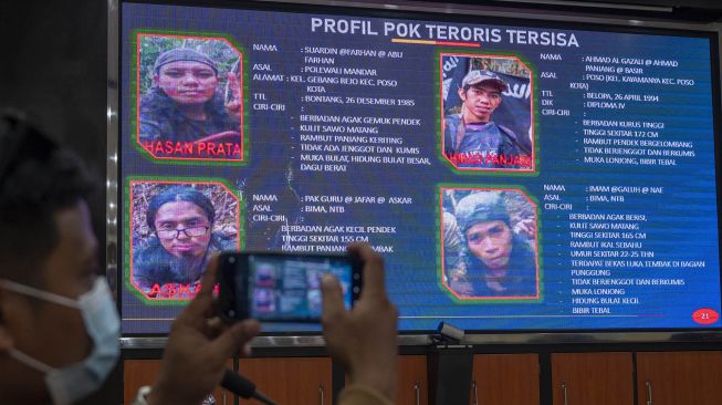 Sejumlah wartawan memperhatikan daftar pencarian orang (DPO) teroris Poso yang ditampilkan di layar pada konferensi pers akhir tahun di Mapolda Sulteng, Jumat (31/12/2021).  ANTARA FOTO/Basri Marzuki