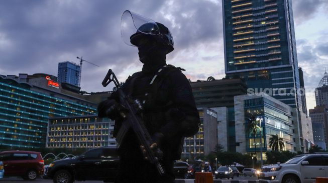 Personel Kepolisian berjaga di kawasan Bundaran HI, Jakarta Pusat, Jumat (31/12/2021). [Suara.com/Alfian Winanto]