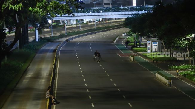 Suasana sepi saat malam pergantian tahun di Jalan Sudirman, Jakarta Pusat, Sabtu (1/1/2022). [Suara.com/Alfian Winanto]