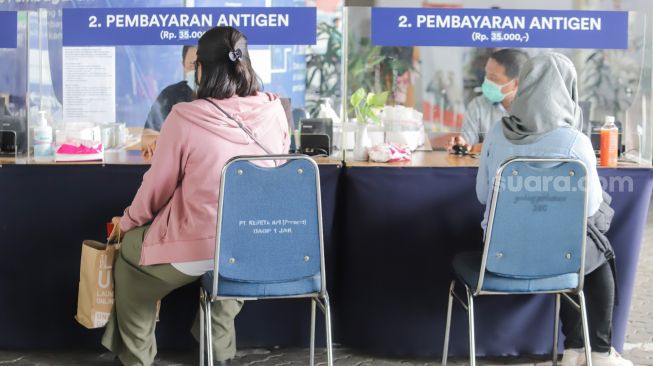 Penumpang membayar untuk Rapid Tes Antigen di Stasiun Gambir, Jakarta Pusat, Sabtu (1/1/2022). [Suara.com/Alfian Winanto]