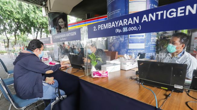 Penumpang membayar untuk Rapid Tes Antigen di Stasiun Gambir, Jakarta Pusat, Sabtu (1/1/2022). [Suara.com/Alfian Winanto]