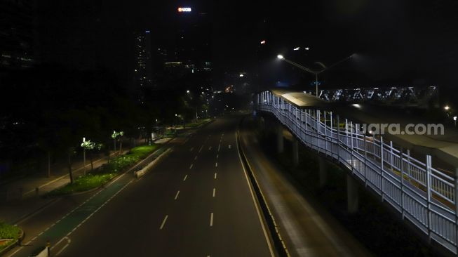 Suasana sepi saat malam pergantian tahun di Jalan Sudirman, Jakarta Pusat, Sabtu (1/1/2022). [Suara.com/Alfian Winanto]