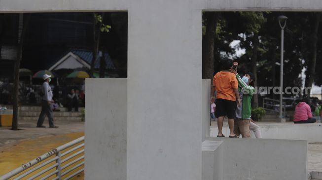 Orang tua mendampingi anaknya bermain di Taman Puring, Jakarta, Minggu (2/1/2022). [Suara.com/Angga Budhiyanto]