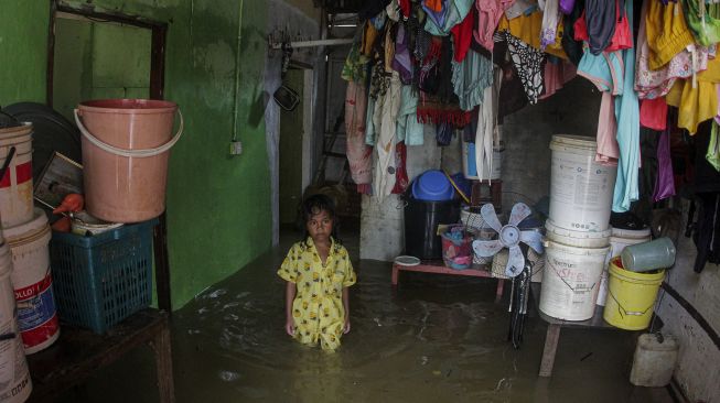 Seorang anak berada di dalam rumahnya yang terendam banjir di salah satu kawasan permukiman di daerah Muka Kuning, Batam, Kepulauan Riau, Minggu (2/1/2022). [ANTARA FOTO/Teguh Prihatna]