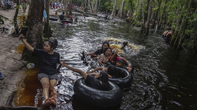 Sejumlah wisatawan bermain air di kawasan pemandian air gambut Danum Bahandang Tangkiling di Palangkaraya, Kalimantan Tengah, Minggu (2/1/2022). [ANTARA FOTO/Makna Zaezar]