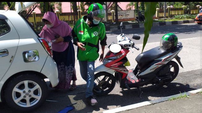 Ojol membantu pemobil yang mengalami pecah ban di jalan (Facebook)