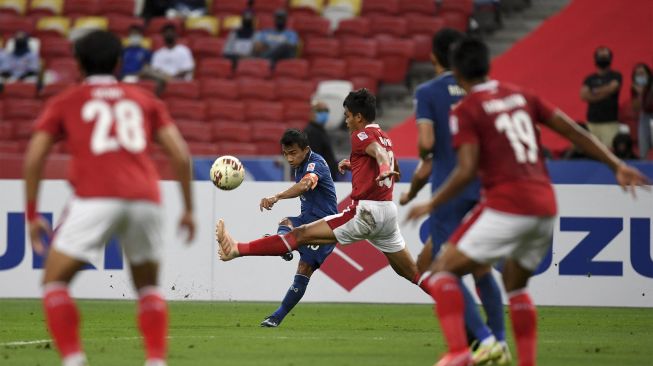 Pemain Thailand Chanathip Songkrasin (kedua kiri) menendang bola melewati pemain Indonesia Rachmat Irianto (tengah) pada pertandingan final sepak bola AFF Suzuki Cup 2020 leg kedua antara Thailand dan Indonesia di Stadion Nasional Singapura, pada (1/12/2022). [ROSLAN RAHMAN / AFP]