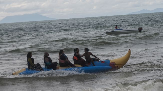 Wisatawan bermain wahana air di Pantai Carita, Pandeglang, Banten, Sabtu (1/1/2022). [ANTARA FOTO/Muhammad Bagus Khoirunas]