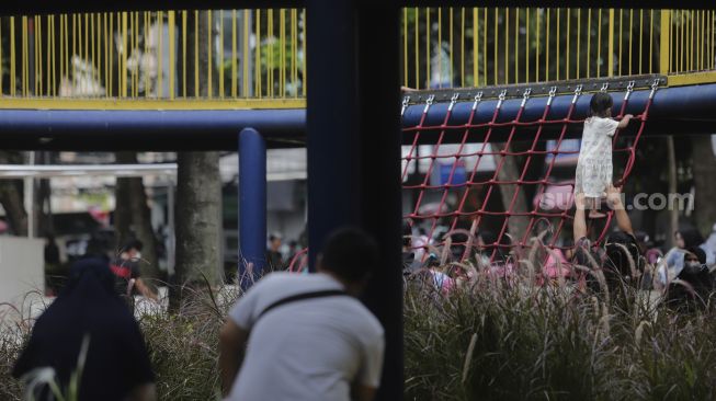 Orang tua mendampingi anaknya bermain di Taman Puring, Jakarta, Minggu (2/1/2022). [Suara.com/Angga Budhiyanto]