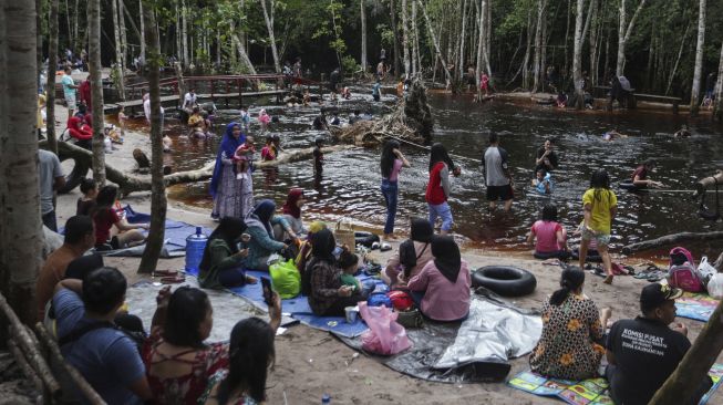 Sejumlah wisatawan berkunjung ke kawasan pemandian air gambut Danum Bahandang Tangkiling di Palangkaraya, Kalimantan Tengah, Minggu (2/1/2022). [ANTARA FOTO/Makna Zaezar]