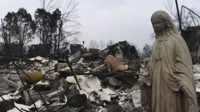 Patung Perawan Maria berada di sebuah rumah yang terbakar di lingkungan The Enclave, Louisville, Colorado, Amerika Serikat, pada (31/12/2021). [JASON CONNOLLY / AFP]