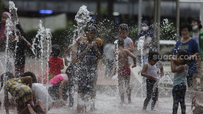 Sejumlah anak bermain air di Taman Puring, Jakarta, Minggu (2/1/2022). [Suara.com/Angga Budhiyanto]