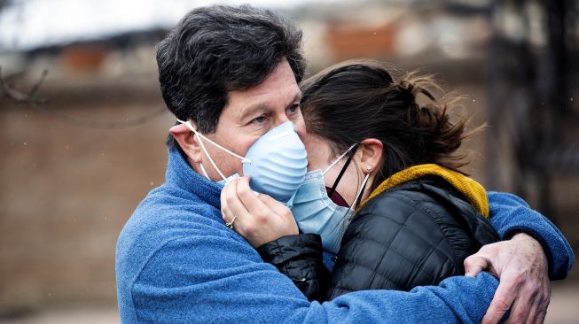 Louie Delaware memeluk putrinya Elise setelah melihat sisa-sisa rumah mereka dihancurkan oleh api di Louisville, Colorado, Amerika Serikat, pada (31/12/2021). [JASON CONNOLLY / AFP]