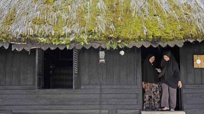 Pengunjung keluar dari pintu Masjid Tuo Kayu Jao di Batang Barus, Gunung Talang, Solok, Sumatera Barat, Senin (3/1/2022). [ANTARA FOTO/Wahdi Septiawan]