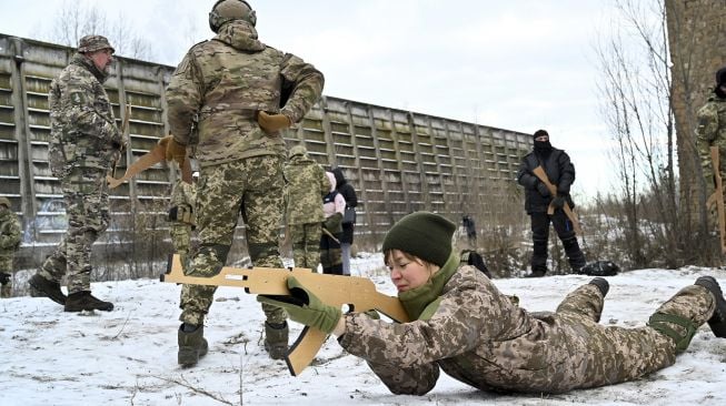 Pasukan Pertahanan Teritorial Ukraina yang merupakan cadangan militer Angkatan Bersenjata Ukraina, memegang replika kayu senapan Kalashnikov selama latihan militer di dekat Kiev, Ukraina, pada (25/12/2021). [SERGEI SUPINSKY / AFP]