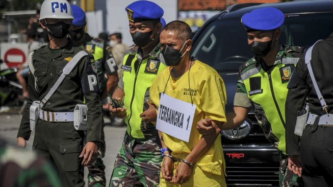 Petugas membawa tersangka dengan inisial P saat rekonstruksi kecelakaan tabrak lari di Jalan Nasional III, Desa Ciaro, Nagreg, Kabupaten Bandung, Jawa Barat, Senin (3/1/2022). [ANTARA FOTO/Raisan Al Farisi]