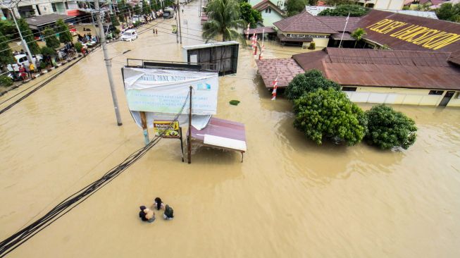 Sejumlah warga berjalan menembus banjir yang melanda Kota Lhoksukon, Aceh Utara, Aceh, Senin (3/1/2022). ANTARA FOTO/Rahmad
